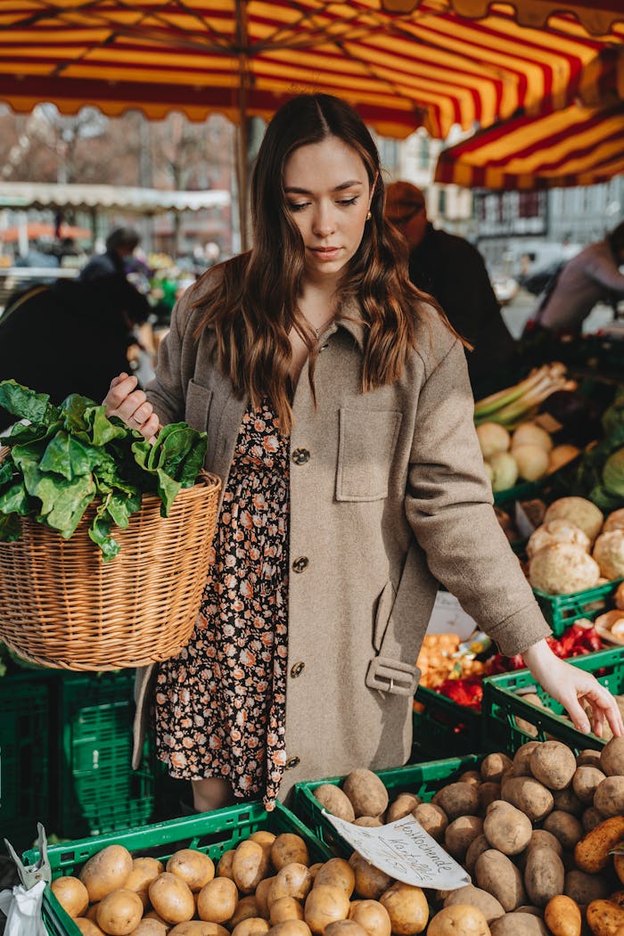 Young woman with basket shopping for fresh vegetables at an outdoor market in Erfurt, Germany.